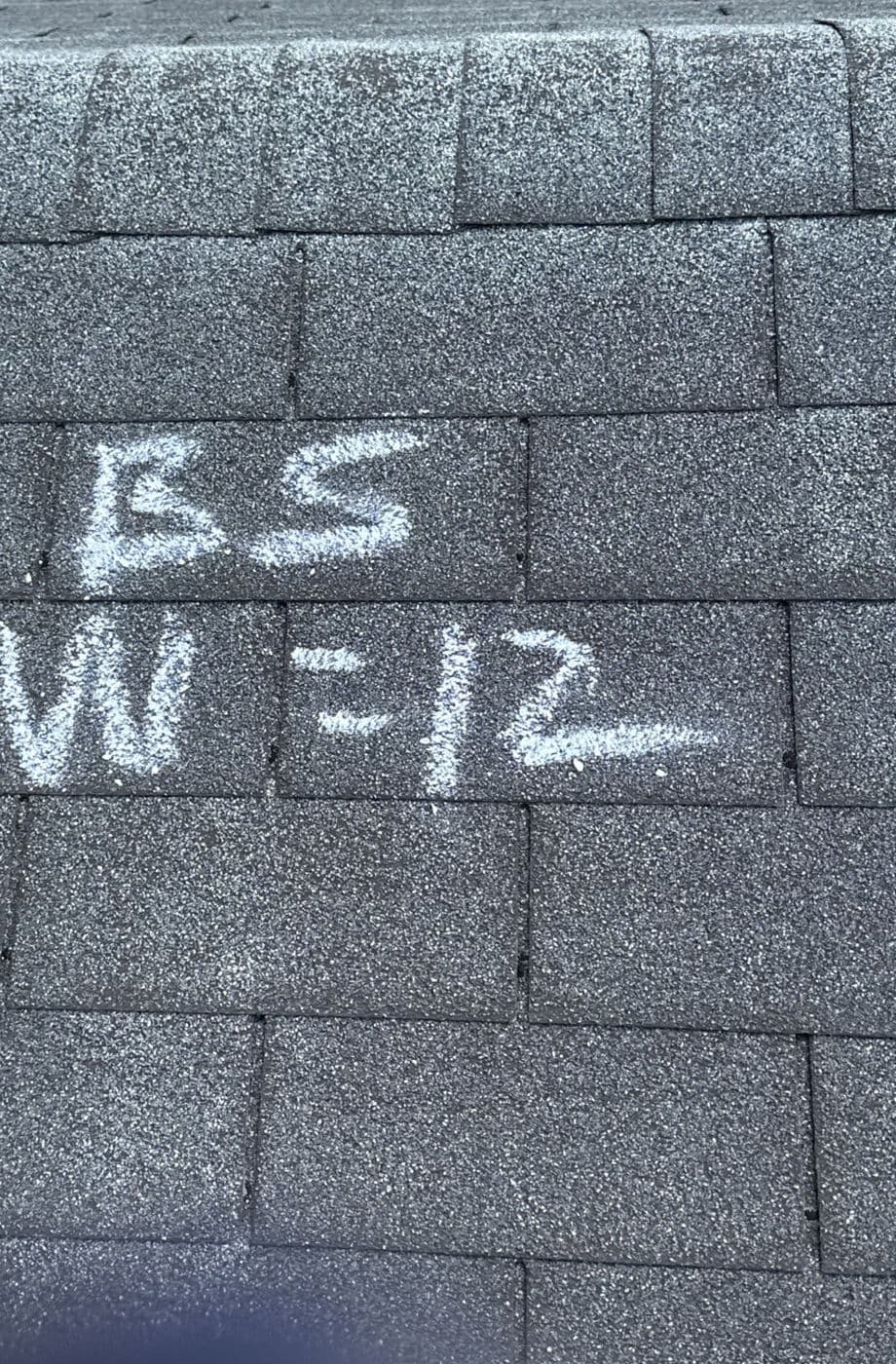 Chalk-marked hail strikes inside a test square on an asphalt shingle roof during an insurance inspection