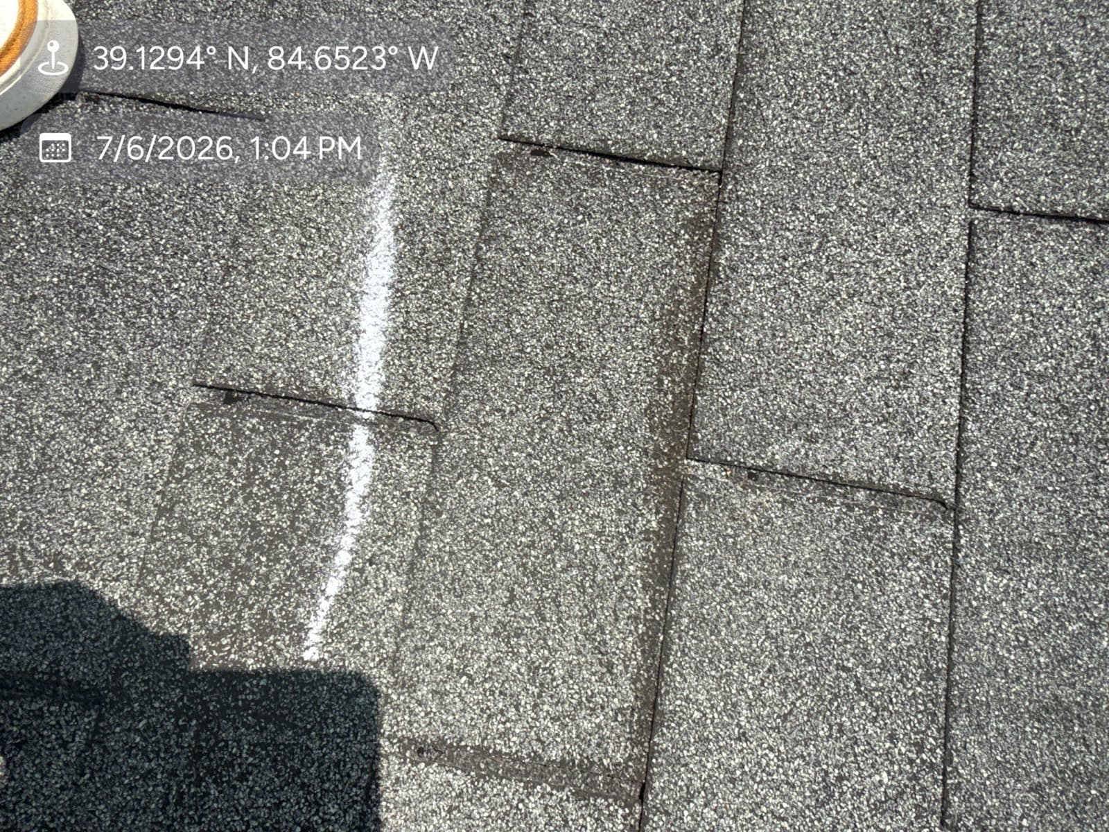 Roof inspector examining and marking hail damage on an asphalt shingle roof